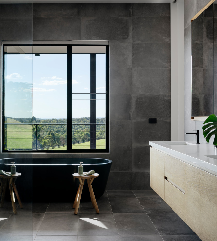 Expansive contemporary master bathroom in Melbourne with flat-panel cabinets, light wood cabinets, a freestanding tub, an open shower, a two-piece toilet, gray tile, porcelain tile, grey walls, porcelain floors, a pedestal sink, quartzite benchtops, grey floor, an open shower, a double vanity and a floating vanity.