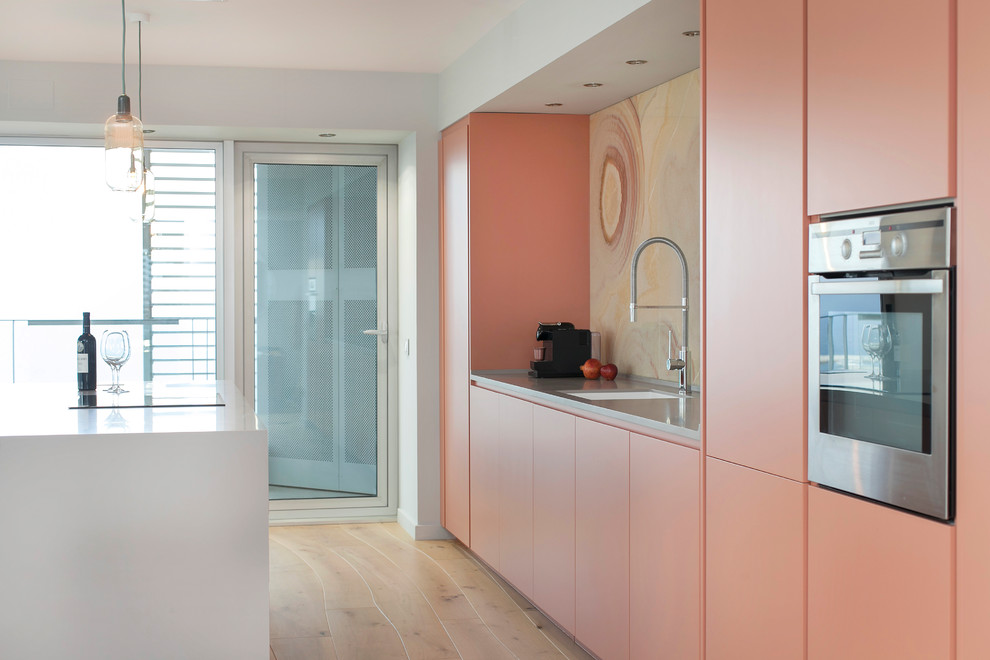 Design ideas for a large contemporary galley kitchen in Other with an integrated sink, flat-panel cabinets, orange cabinets, solid surface benchtops, yellow splashback, marble splashback, stainless steel appliances, medium hardwood floors and with island.