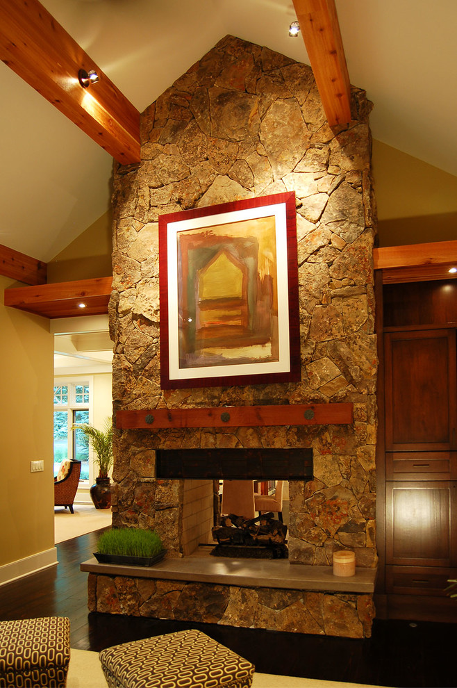 Inspiration for a mid-sized arts and crafts formal enclosed living room in Grand Rapids with yellow walls, dark hardwood floors, a two-sided fireplace, a stone fireplace surround and a built-in media wall.