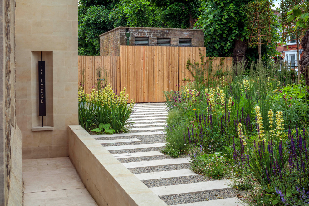 Cette image montre un jardin avant design de taille moyenne et au printemps avec une exposition ensoleillée, des pavés en pierre naturelle et une clôture en bois.