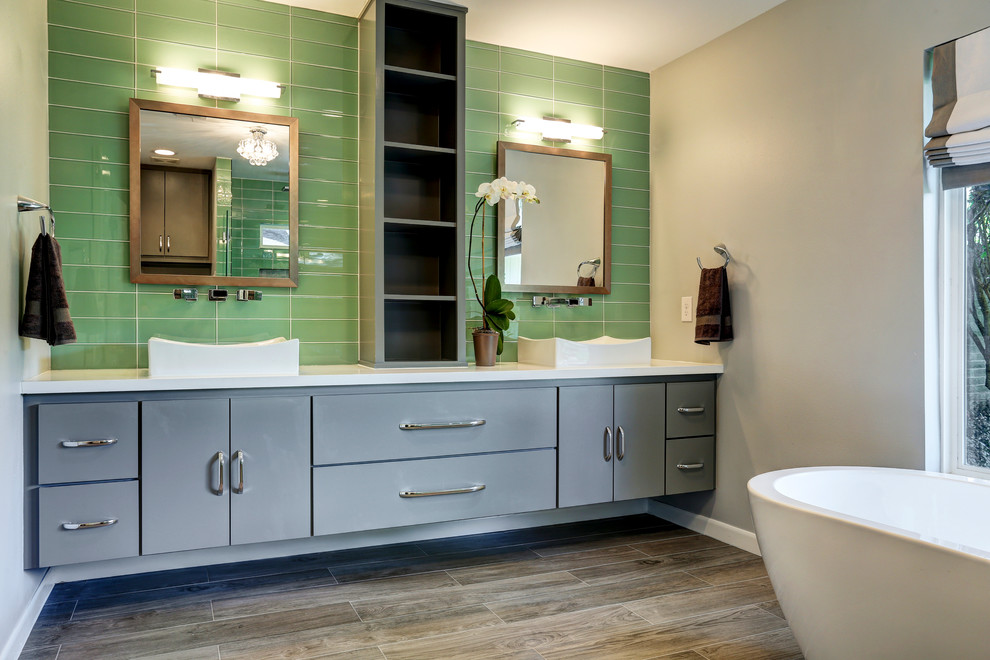Inspiration for a mid-sized contemporary master bathroom in Houston with a freestanding tub, a double shower, green tile, glass tile, a console sink, flat-panel cabinets, grey cabinets, engineered quartz benchtops, a one-piece toilet, white walls and ceramic floors.