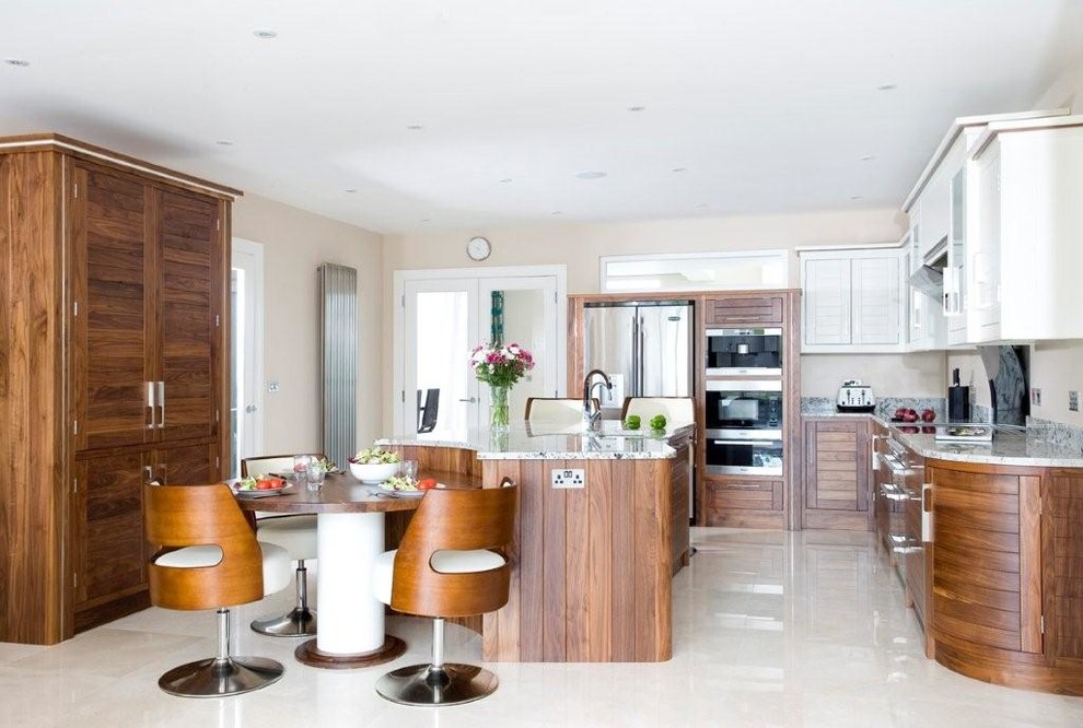 Photo of a large beach style u-shaped eat-in kitchen in Other with an undermount sink, flat-panel cabinets, dark wood cabinets, granite benchtops, black splashback, stone slab splashback, black appliances, marble floors and with island.