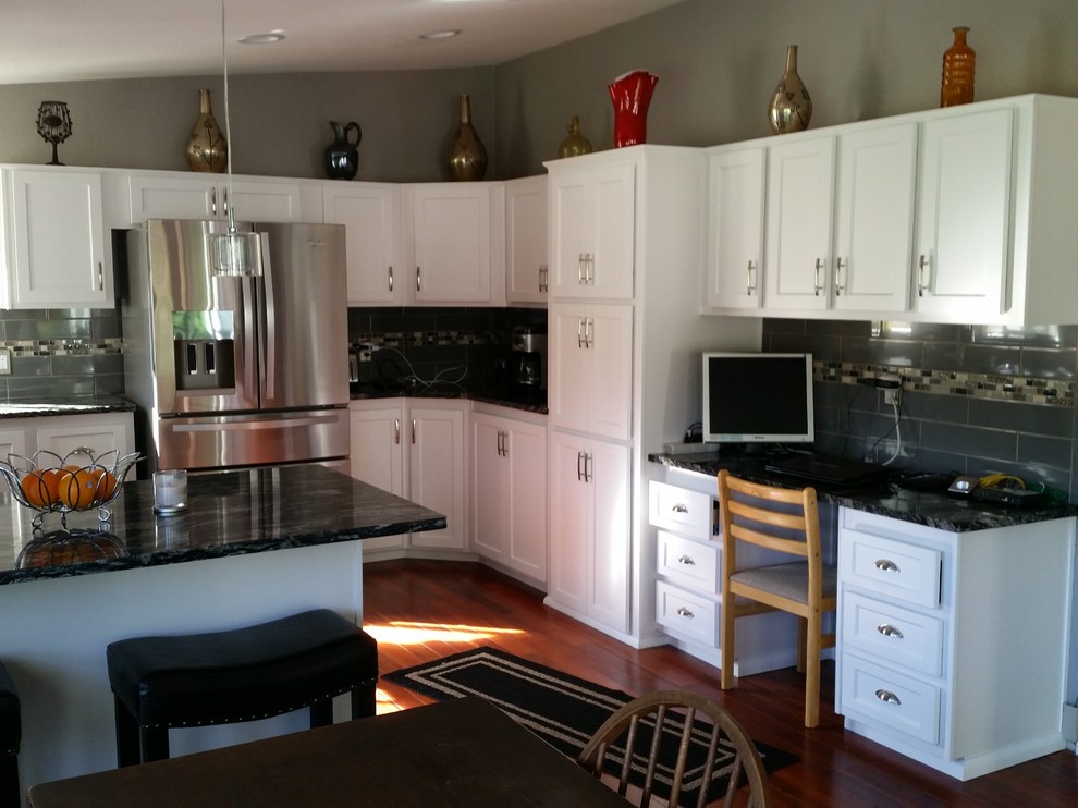 Mid-sized transitional u-shaped medium tone wood floor and brown floor enclosed kitchen photo in Seattle with an undermount sink, recessed-panel cabinets, white cabinets, granite countertops, gray backsplash, ceramic backsplash, stainless steel appliances, a peninsula and black countertops