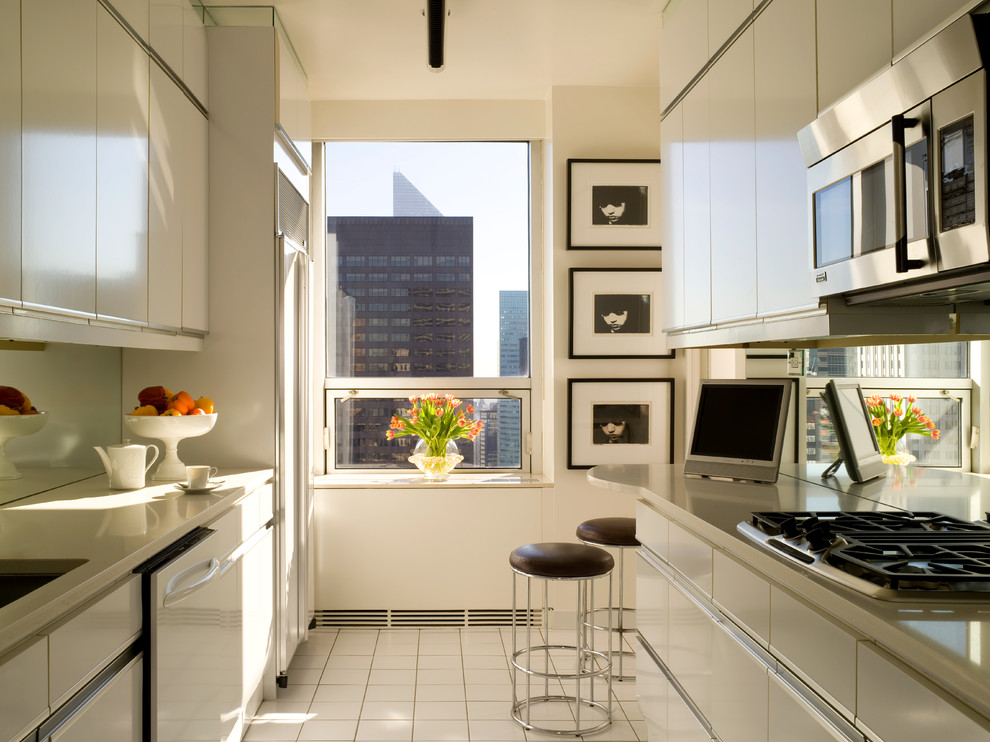 Small contemporary galley eat-in kitchen in New York with an undermount sink, flat-panel cabinets, beige cabinets, mirror splashback, stainless steel appliances and no island.