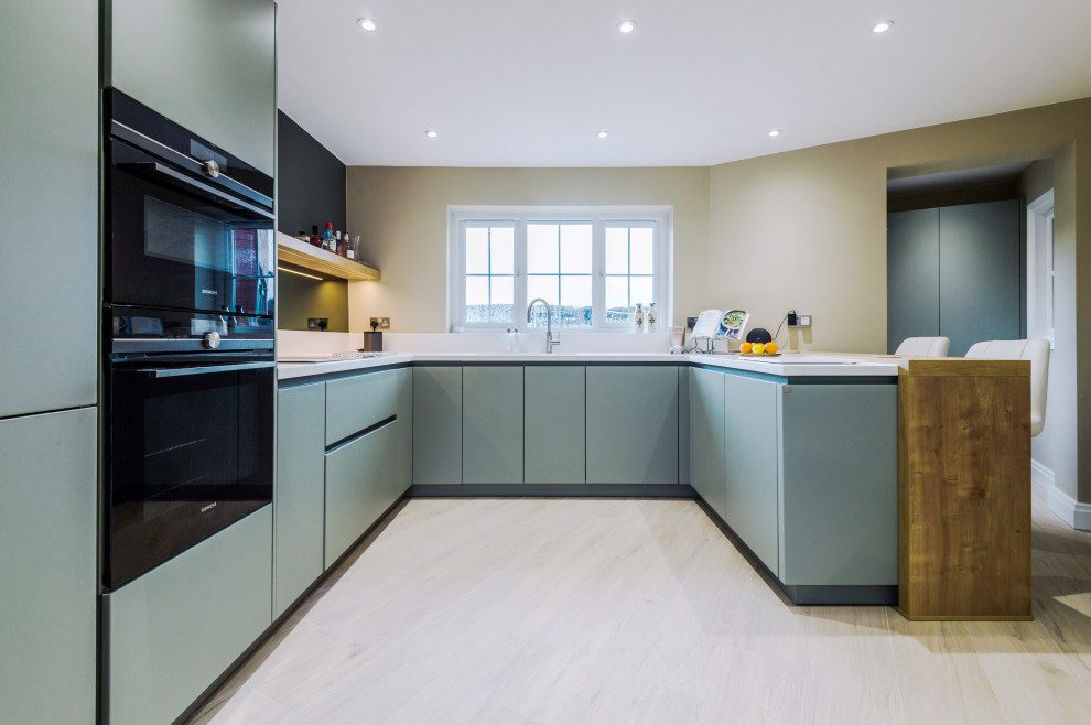 Photo of a mid-sized contemporary u-shaped kitchen in Manchester with a drop-in sink, blue cabinets and porcelain floors.