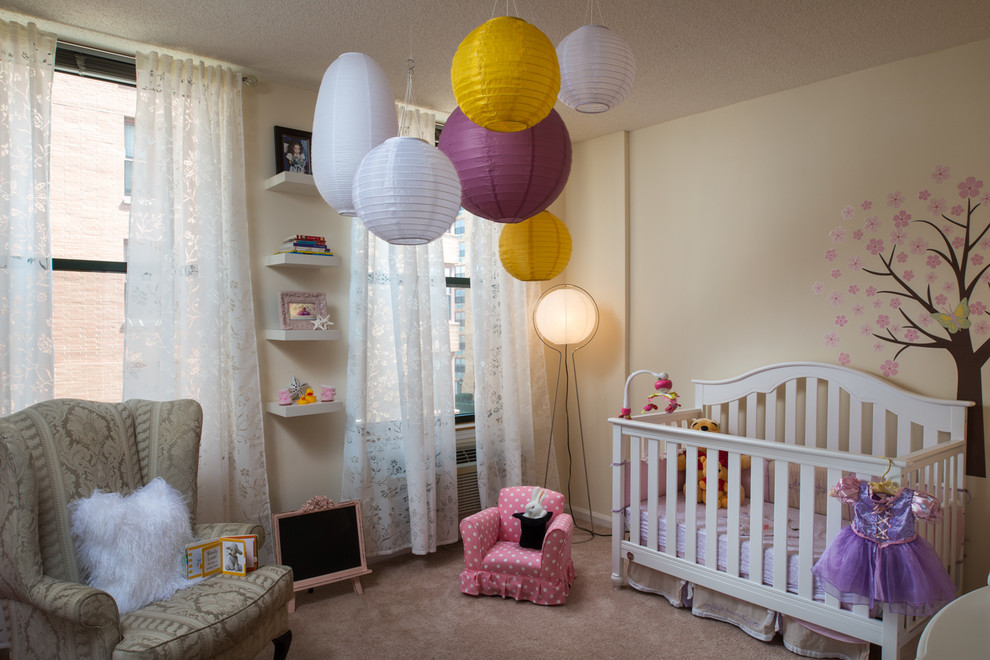 Design ideas for a transitional nursery for girls in New York with beige walls and carpet.