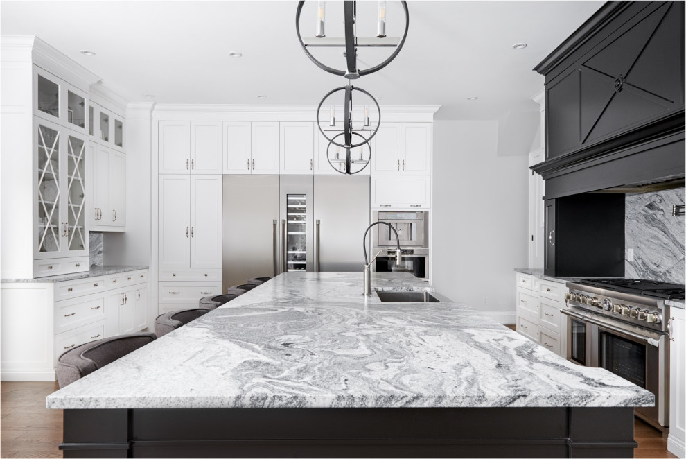 Inspiration for a huge transitional light wood floor and brown floor eat-in kitchen remodel in Toronto with a farmhouse sink, shaker cabinets, white cabinets, granite countertops, gray backsplash, granite backsplash, stainless steel appliances, an island and gray countertops