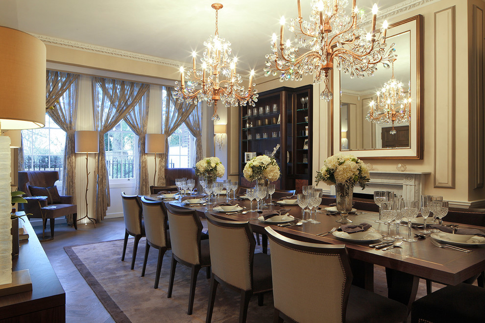 This is an example of a transitional dining room in London with beige walls, dark hardwood floors, a standard fireplace and a stone fireplace surround.