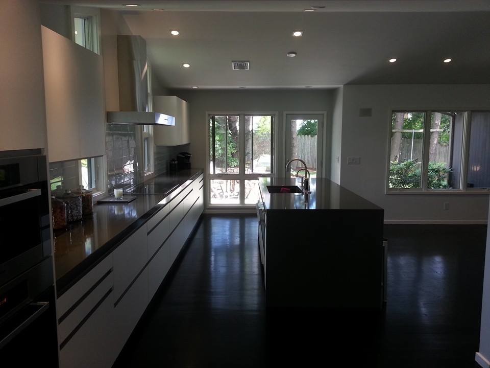 Mid-sized transitional single-wall medium tone wood floor open concept kitchen photo in Boston with a drop-in sink, flat-panel cabinets, white cabinets, granite countertops, white backsplash, stone tile backsplash, stainless steel appliances and an island