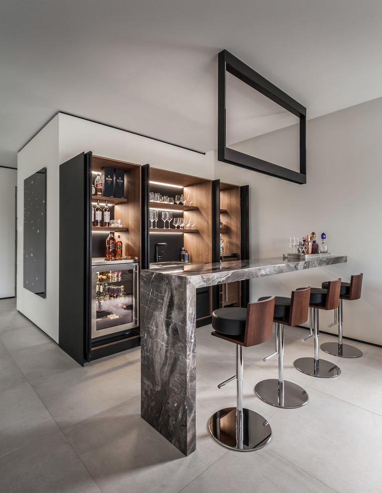 Design ideas for a large contemporary galley wet bar in Miami with dark wood cabinets, marble benchtops, porcelain floors, grey floor, a drop-in sink, black splashback, grey benchtop and open cabinets.