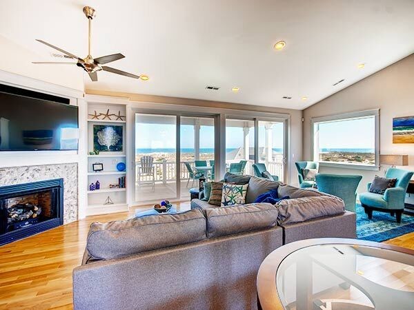Photo of a mid-sized beach style formal open concept living room in Other with beige walls, medium hardwood floors, a corner fireplace, a tile fireplace surround and a wall-mounted tv.
