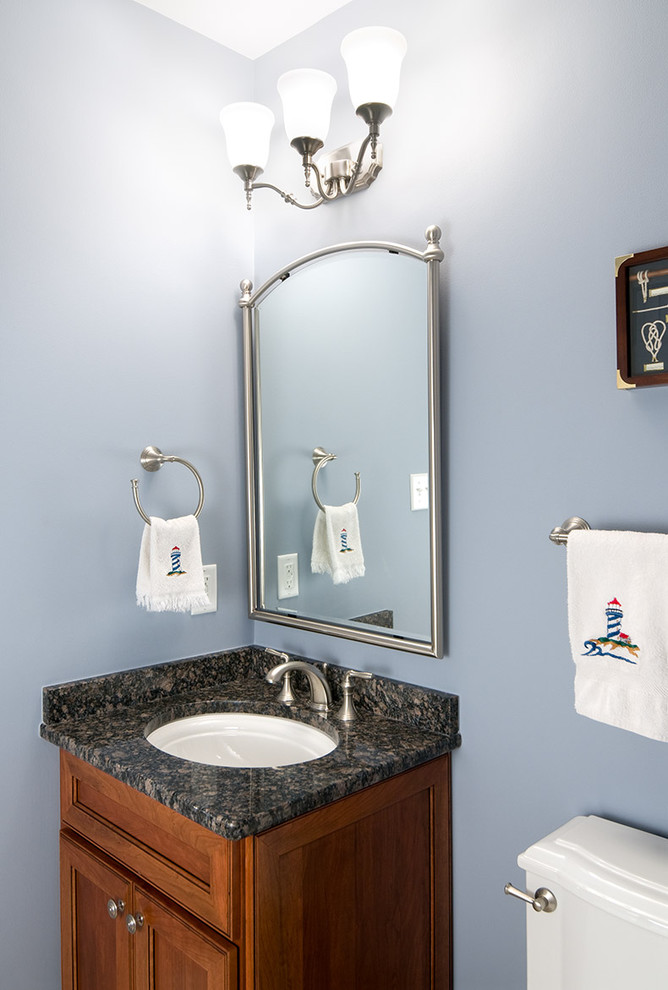 This is an example of a mid-sized traditional powder room in Other with an undermount sink, a one-piece toilet, blue walls, recessed-panel cabinets, medium wood cabinets and granite benchtops.