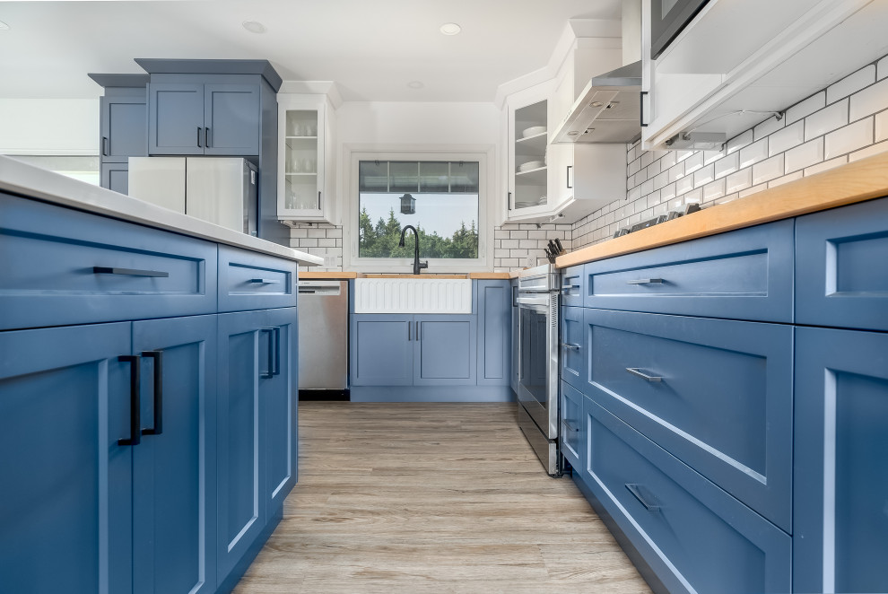 Inspiration for a transitional kitchen remodel in Edmonton with shaker cabinets, blue cabinets, quartzite countertops, subway tile backsplash, stainless steel appliances, an island and white countertops