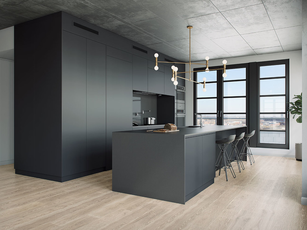 This is an example of a large modern kitchen in Montreal with flat-panel cabinets, grey cabinets, laminate benchtops, glass tile splashback, light hardwood floors, with island, grey splashback and stainless steel appliances.