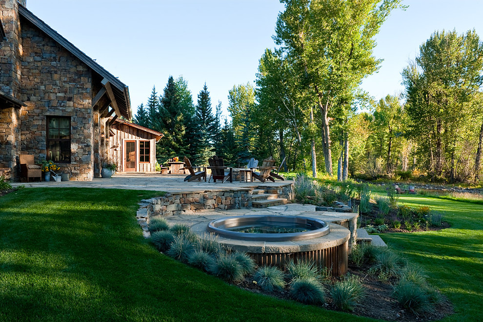 This is an example of a large country backyard patio in Boise with a fire feature, natural stone pavers and no cover.