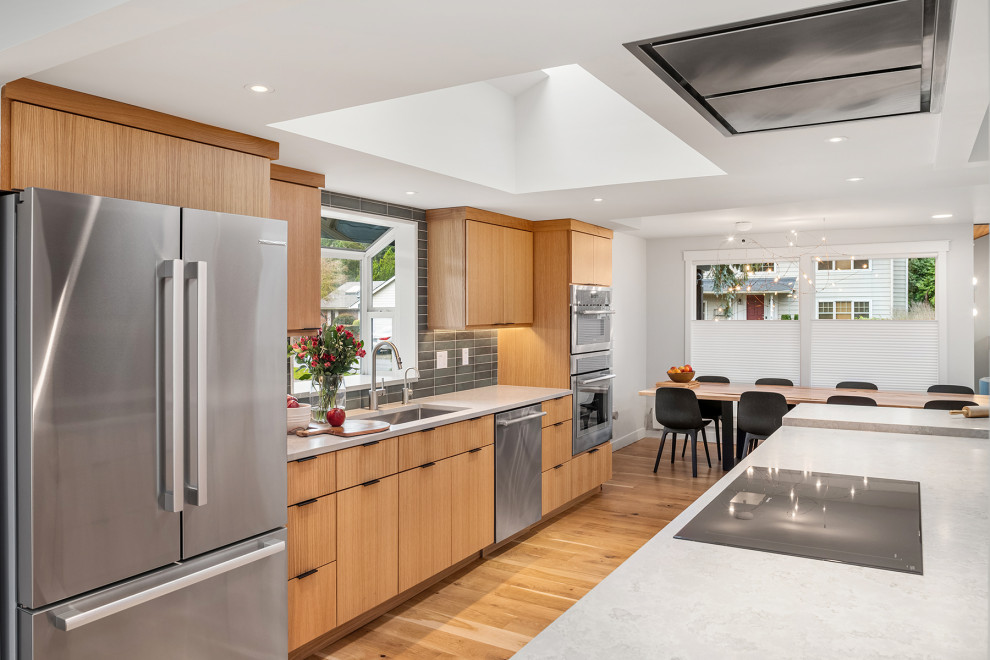 Eat-in kitchen - mid-sized transitional light wood floor eat-in kitchen idea in Seattle with an undermount sink, flat-panel cabinets, light wood cabinets, quartz countertops, green backsplash, ceramic backsplash, stainless steel appliances and an island