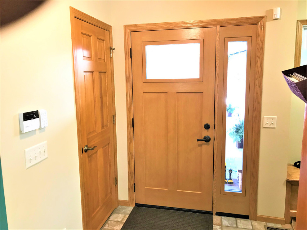 Immagine di una grande porta d'ingresso design con pareti gialle, una porta in legno chiaro e pavimento multicolore