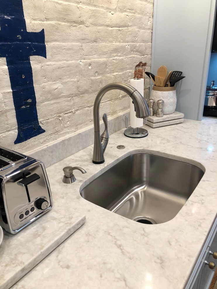 Inspiration for a small transitional single-wall light wood floor and brown floor open concept kitchen remodel with an undermount sink, recessed-panel cabinets, gray cabinets, marble countertops, white backsplash, brick backsplash, stainless steel appliances, no island and gray countertops