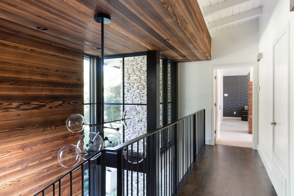 This is an example of a large contemporary hallway in Austin with white walls, medium hardwood floors and brown floor.