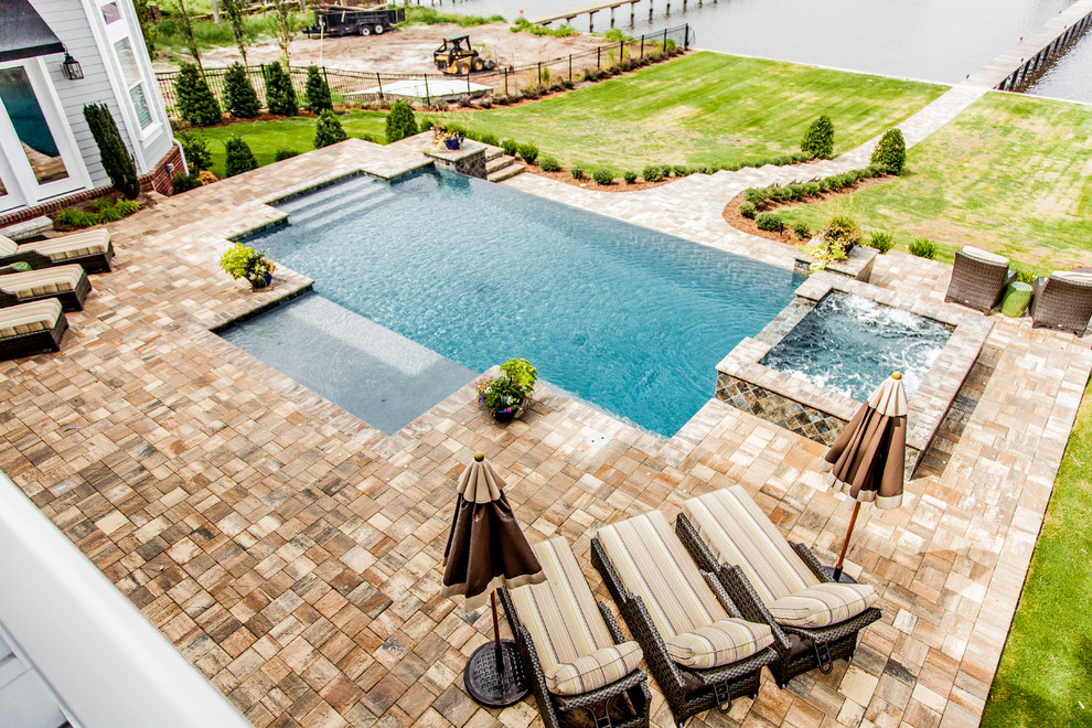 Large contemporary backyard rectangular lap pool in Jacksonville with a hot tub and natural stone pavers.