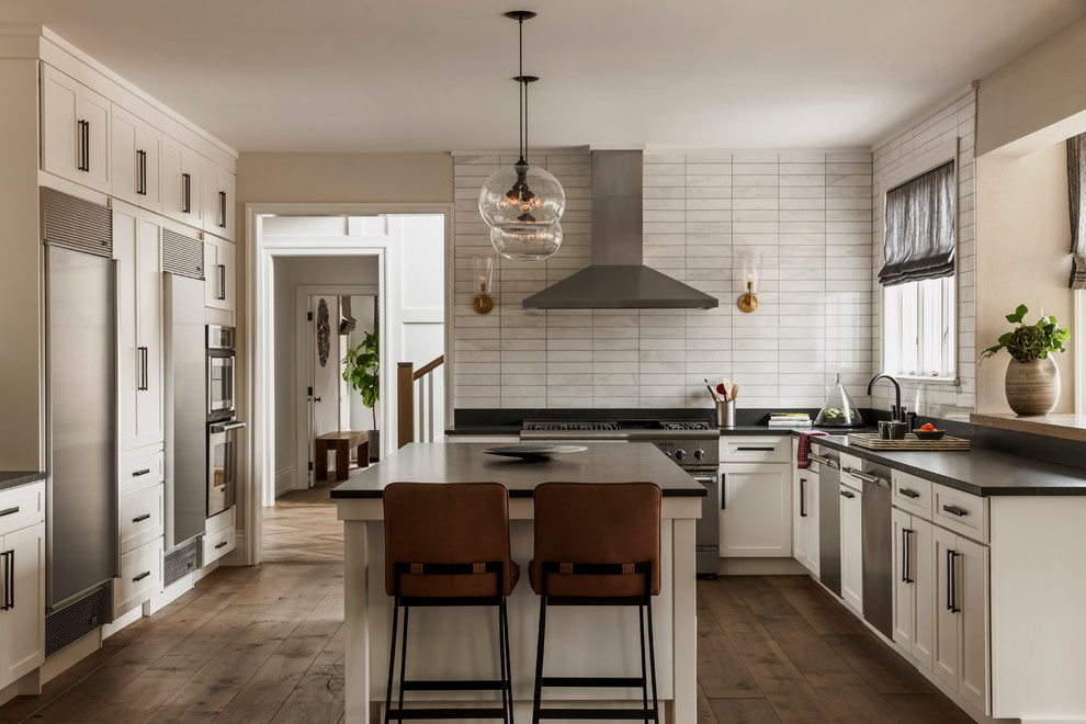 Design ideas for a transitional l-shaped separate kitchen in Philadelphia with shaker cabinets, white cabinets, white splashback, stainless steel appliances, medium hardwood floors, with island, an undermount sink and porcelain splashback.