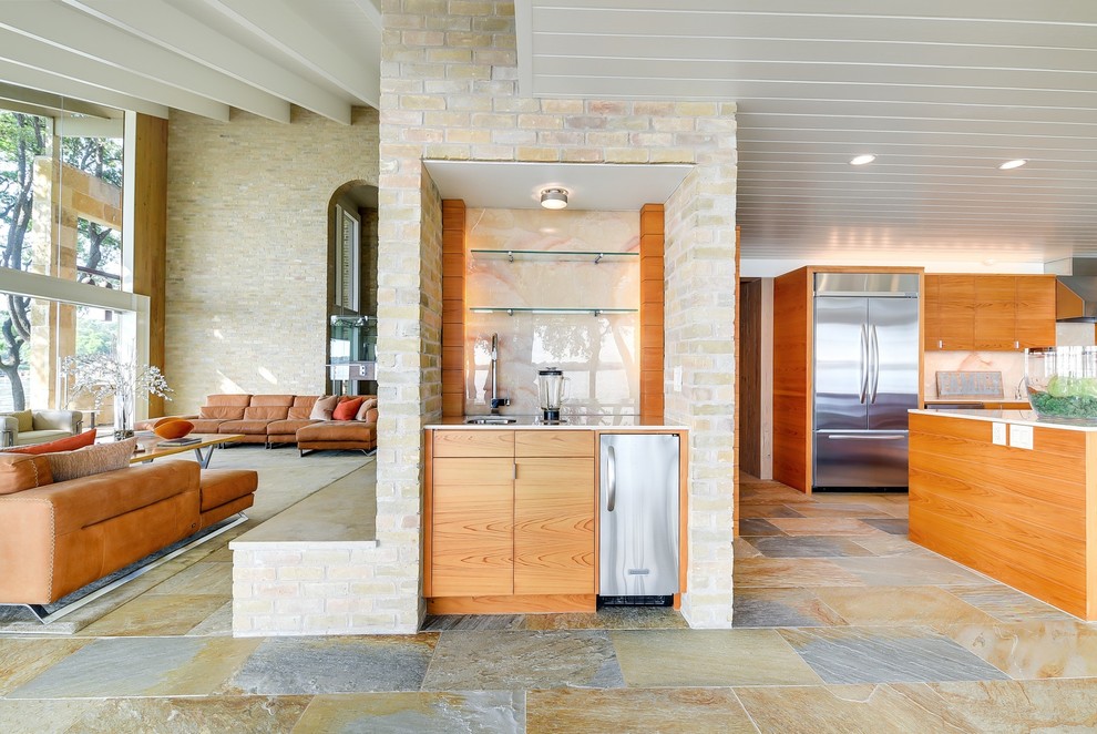 Photo of a small midcentury single-wall wet bar in Austin with an undermount sink, flat-panel cabinets, medium wood cabinets, glass sheet splashback, multi-coloured floor, white benchtop and slate floors.