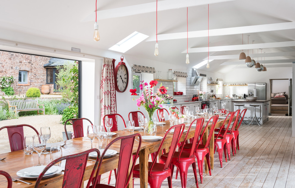 Foto di una grande sala da pranzo aperta verso il soggiorno country con pareti bianche e pavimento in legno verniciato