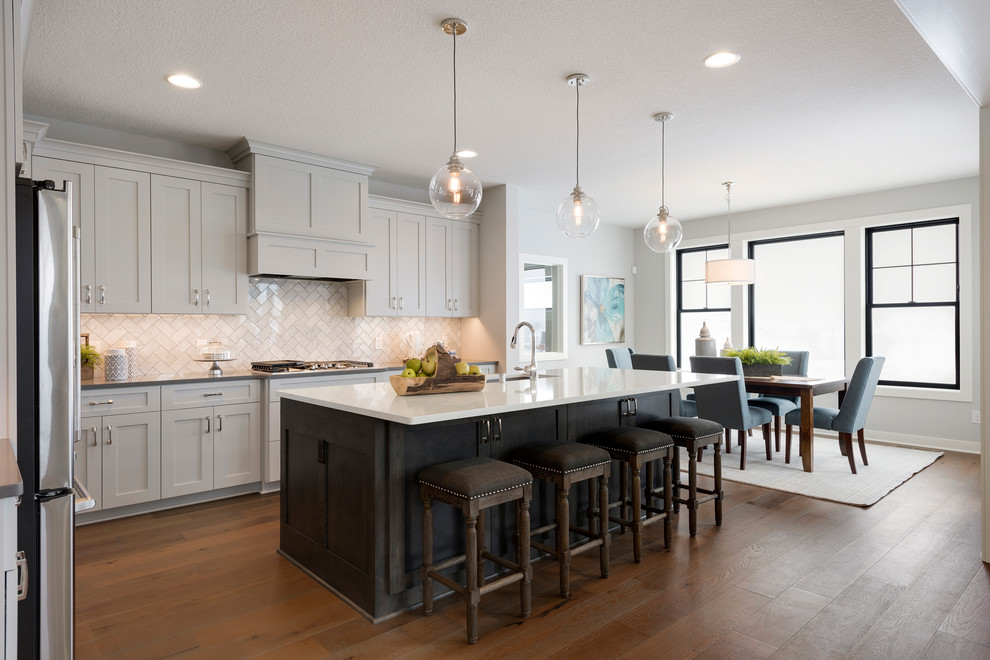 Design ideas for a transitional l-shaped eat-in kitchen in Minneapolis with shaker cabinets, grey cabinets, white splashback, medium hardwood floors, with island and brown floor.