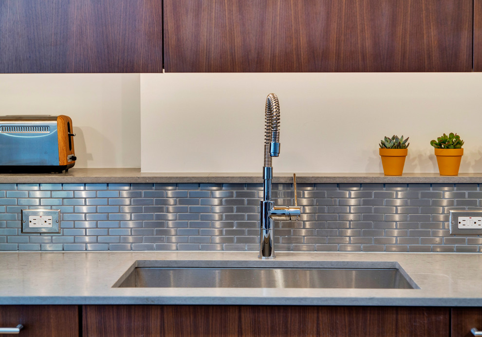 Photo of a contemporary l-shaped eat-in kitchen in New York with an undermount sink, flat-panel cabinets, medium wood cabinets, quartz benchtops, metallic splashback, metal splashback and stainless steel appliances.