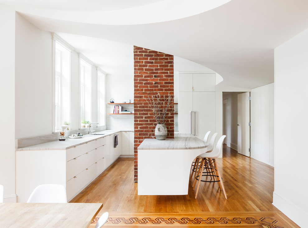 This is an example of a mid-sized contemporary l-shaped open plan kitchen in Boston with flat-panel cabinets, white cabinets, panelled appliances, medium hardwood floors, with island and brown floor.