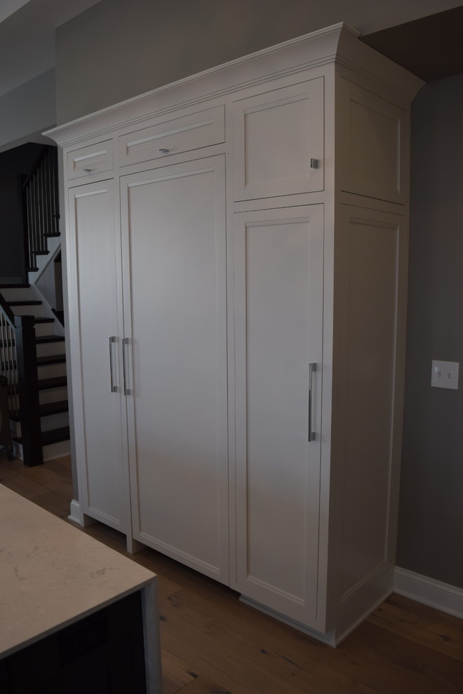 Large transitional l-shaped light wood floor and multicolored floor eat-in kitchen photo in Chicago with beaded inset cabinets, white cabinets, quartz countertops, black backsplash, ceramic backsplash, stainless steel appliances and an island
