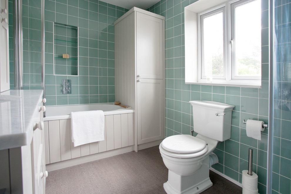 Mid-sized traditional kids bathroom in Kent with recessed-panel cabinets, grey cabinets, a drop-in tub, a corner shower, a wall-mount toilet, green tile, porcelain tile, green walls, vinyl floors, a drop-in sink and marble benchtops.