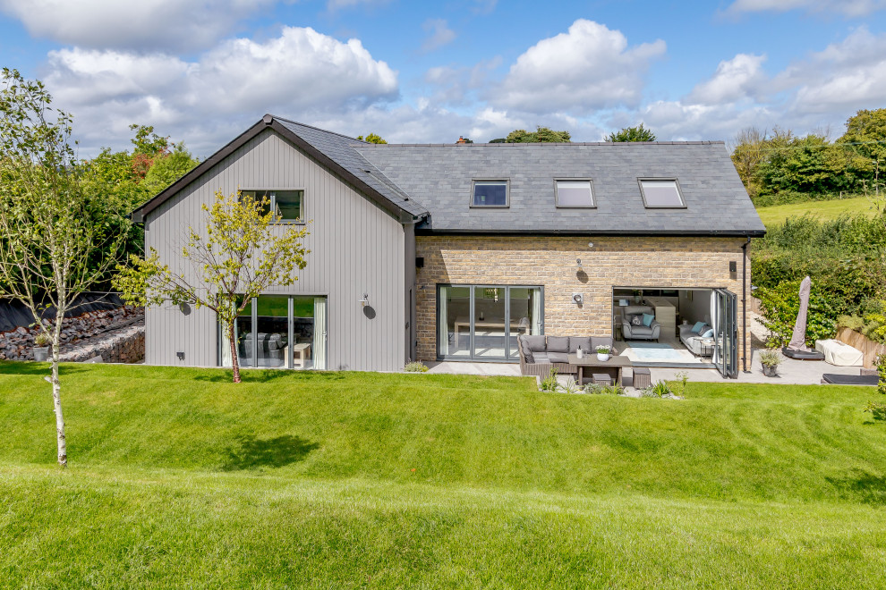 Inspiration for a mid-sized country two-storey beige house exterior in Devon with mixed siding, a grey roof and board and batten siding.