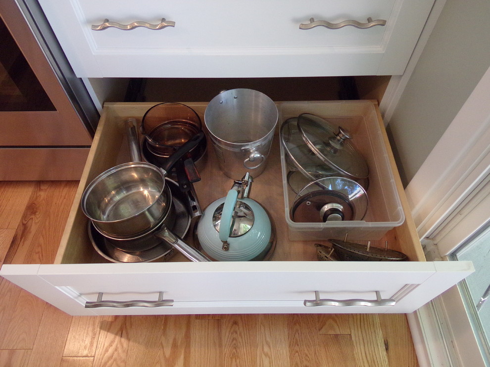 Example of a mid-sized transitional l-shaped light wood floor enclosed kitchen design with an undermount sink, flat-panel cabinets, white cabinets, granite countertops, white backsplash, subway tile backsplash, stainless steel appliances and no island