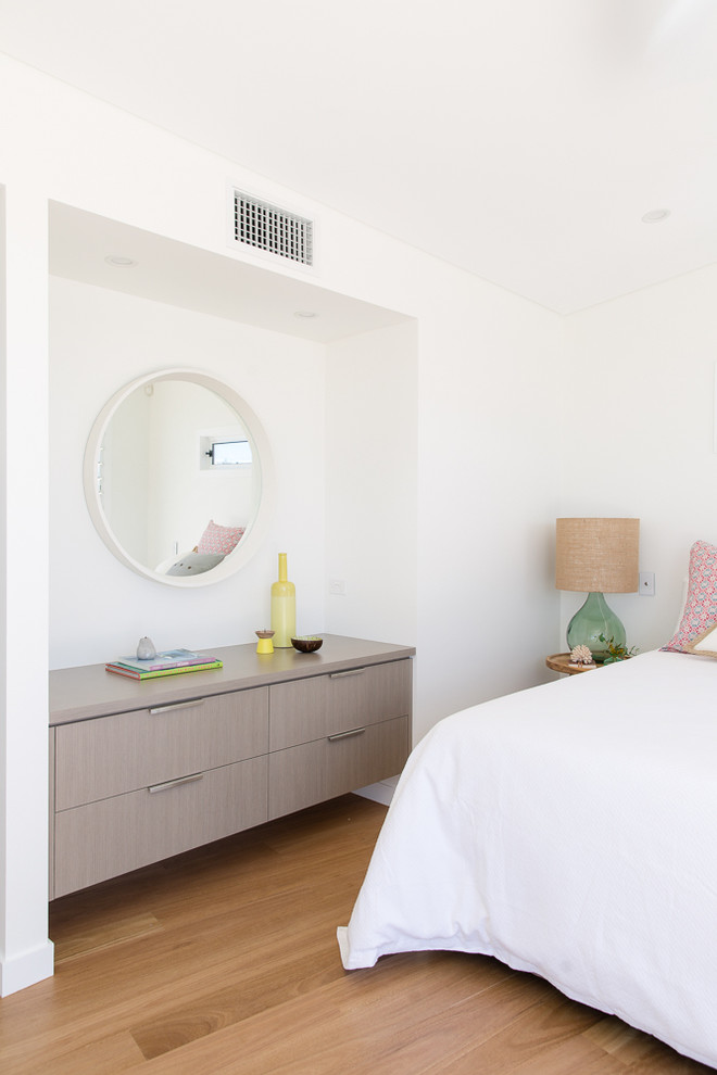 Small modern master bedroom in Sydney with white walls and light hardwood floors.