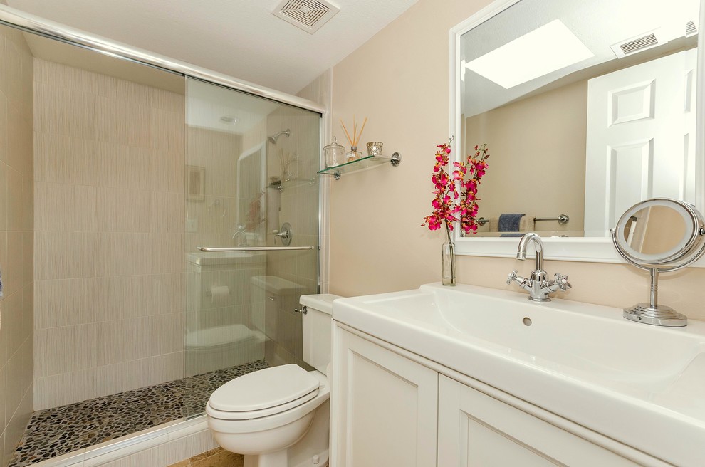 Inspiration for a mid-sized mediterranean 3/4 bathroom in Phoenix with shaker cabinets, white cabinets, solid surface benchtops, an alcove shower, a two-piece toilet, beige walls and porcelain floors.