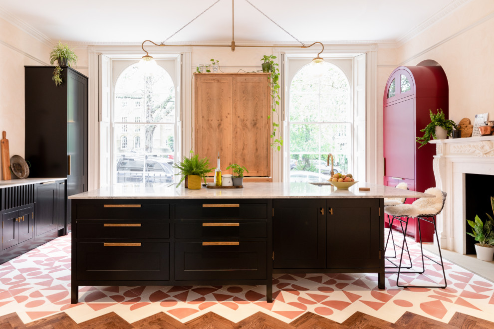 Idée de décoration pour une cuisine bohème en U avec un évier encastré, un placard à porte shaker, des portes de placard noires, îlot, un sol multicolore et un plan de travail gris.