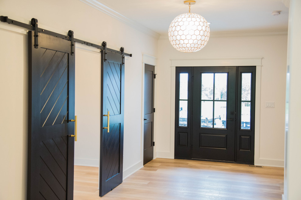 Идея дизайна: большая входная дверь в классическом стиле с белыми стенами, светлым паркетным полом, одностворчатой входной дверью, черной входной дверью и коричневым полом