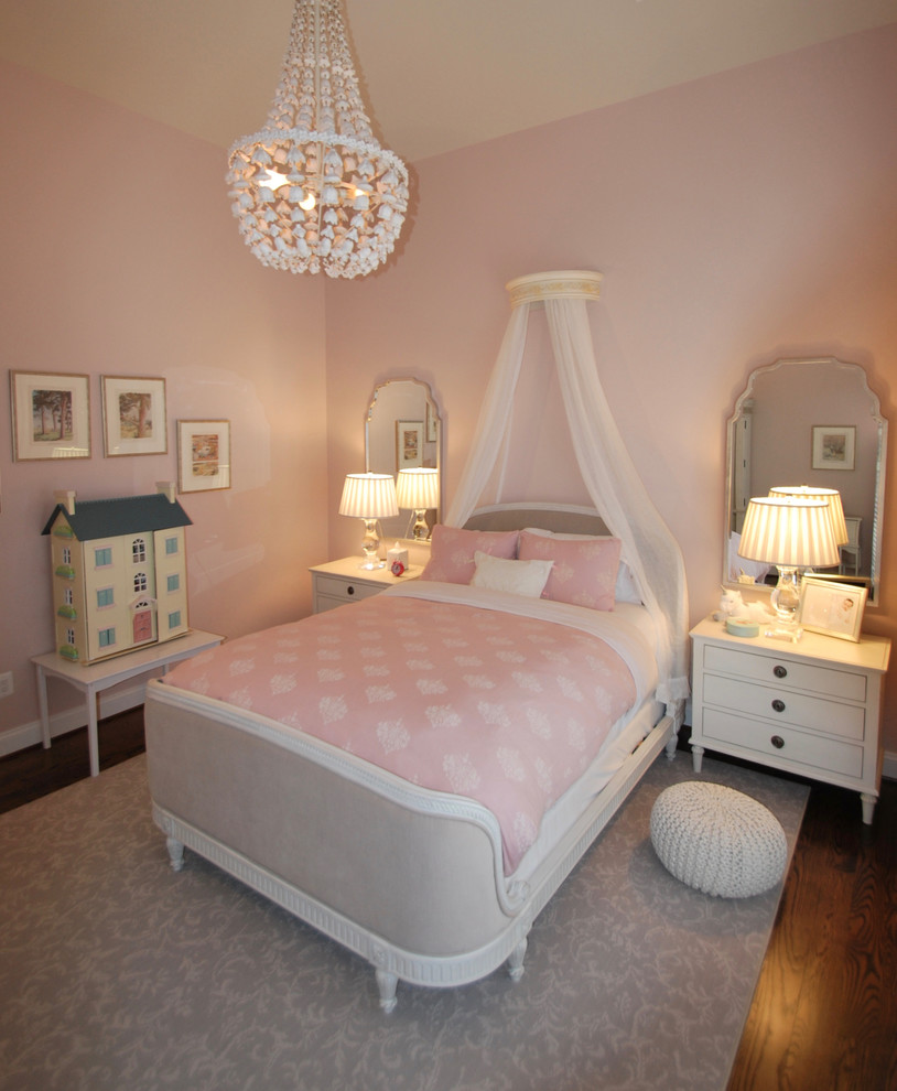 This is an example of a mid-sized traditional kids' bedroom for kids 4-10 years old and girls in DC Metro with pink walls, medium hardwood floors and brown floor.