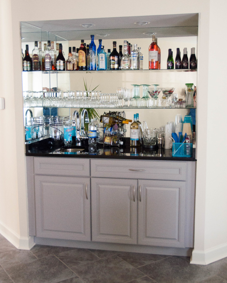 Photo of a mid-sized contemporary u-shaped home bar in Philadelphia with an undermount sink, flat-panel cabinets, grey cabinets, granite benchtops, white splashback, mosaic tile splashback and porcelain floors.