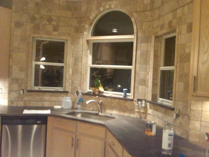 Open concept kitchen - mid-sized transitional galley concrete floor open concept kitchen idea in St Louis with a farmhouse sink, shaker cabinets, medium tone wood cabinets, granite countertops, white backsplash, ceramic backsplash, stainless steel appliances and an island