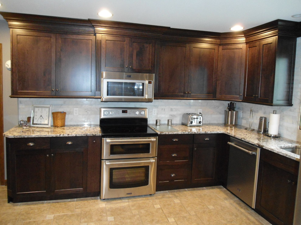 Mid-sized transitional u-shaped eat-in kitchen photo with an undermount sink, flat-panel cabinets, dark wood cabinets, granite countertops, gray backsplash, subway tile backsplash, stainless steel appliances and an island