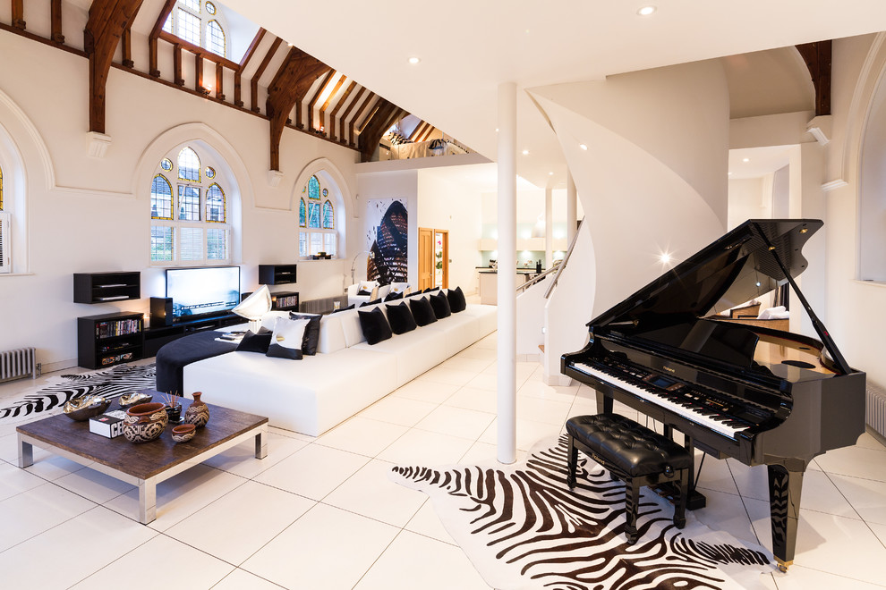 This is an example of a contemporary open concept living room in London with a music area, white walls, no fireplace and a freestanding tv.