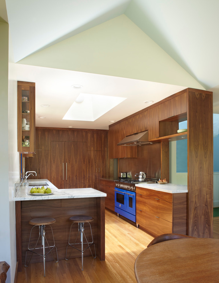 Design ideas for a modern galley eat-in kitchen in San Francisco with dark wood cabinets, marble benchtops, coloured appliances, light hardwood floors and flat-panel cabinets.