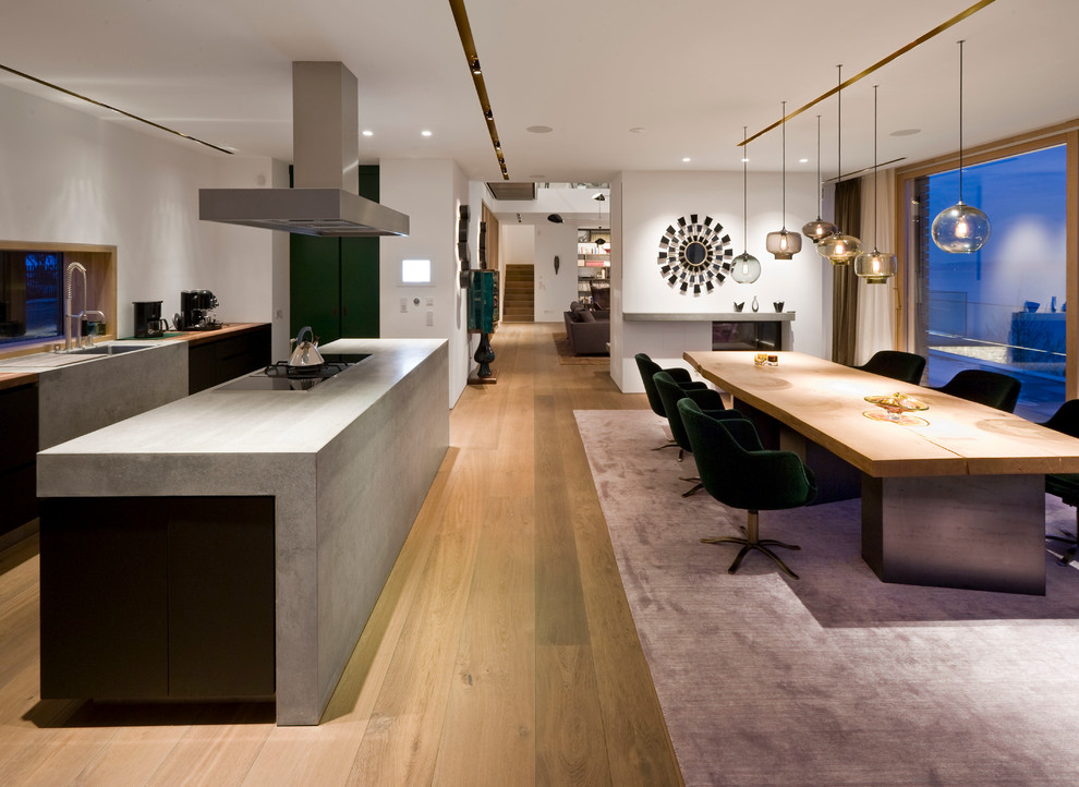 Photo of a mid-sized contemporary single-wall open plan kitchen in Munich with a drop-in sink, flat-panel cabinets, black cabinets, concrete benchtops, medium hardwood floors and with island.