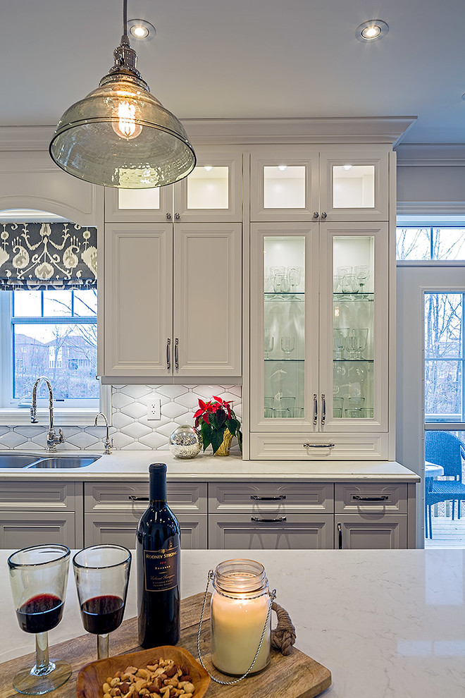 Inspiration for a mid-sized transitional l-shaped enclosed kitchen remodel in Toronto with white cabinets, quartz countertops and an island