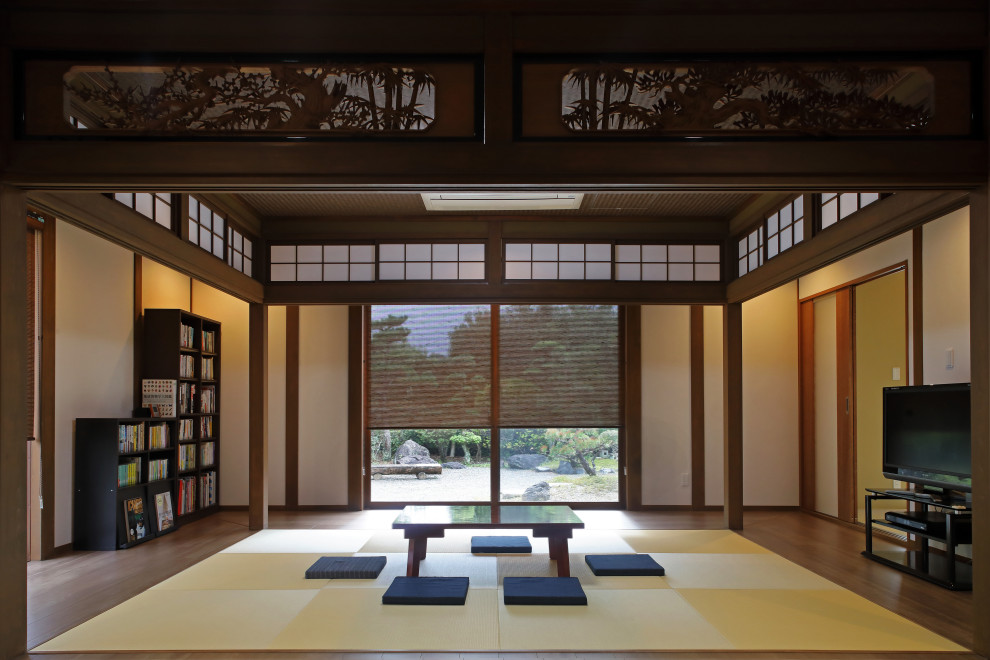 他の地域にある高級な巨大な和風のおしゃれなオープンリビング (ライブラリー、白い壁、無垢フローリング、据え置き型テレビ、茶色い床、壁紙) の写真