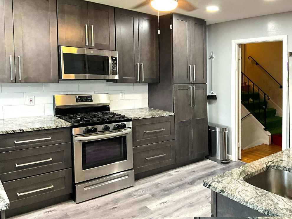This is an example of a small traditional l-shaped open plan kitchen in Baltimore with an undermount sink, shaker cabinets, dark wood cabinets, granite benchtops, white splashback, ceramic splashback, stainless steel appliances, laminate floors, a peninsula and beige floor.