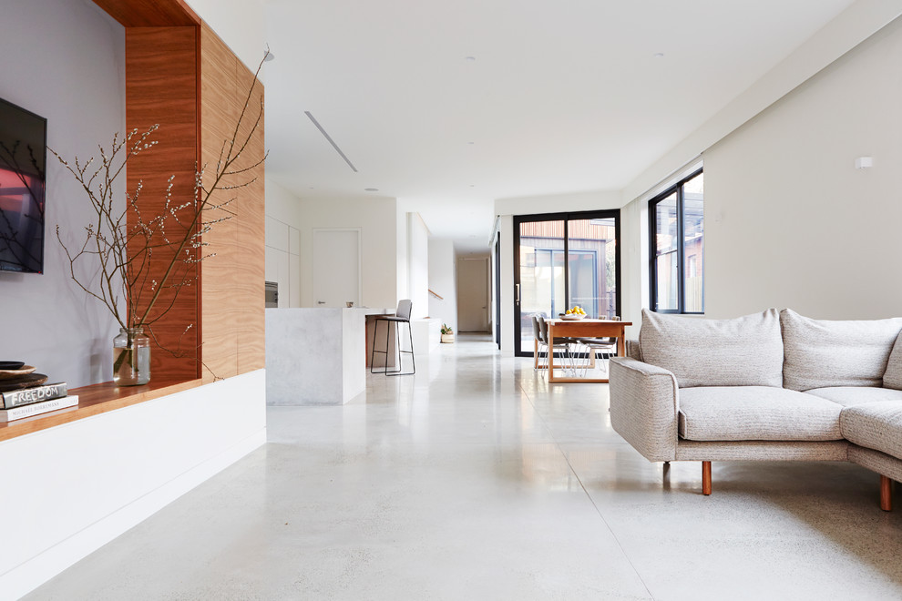 This is an example of a contemporary open concept living room in Melbourne with white walls, concrete floors and a wall-mounted tv.