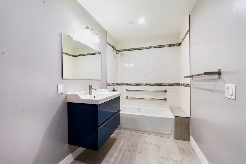 Mid-sized contemporary master bathroom in Los Angeles with grey cabinets, a shower/bathtub combo, white tile, ceramic tile, grey walls and porcelain floors.